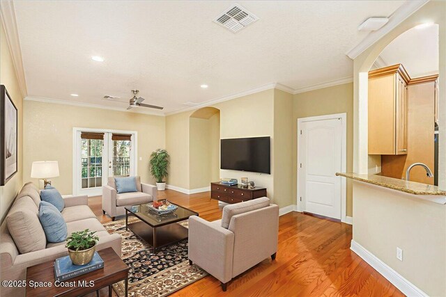 1390 Isabella Dr Unit 106, Melbourne, FL 32935 - living area with arched walkways, light wood finished floors, crown molding, and recessed lighting