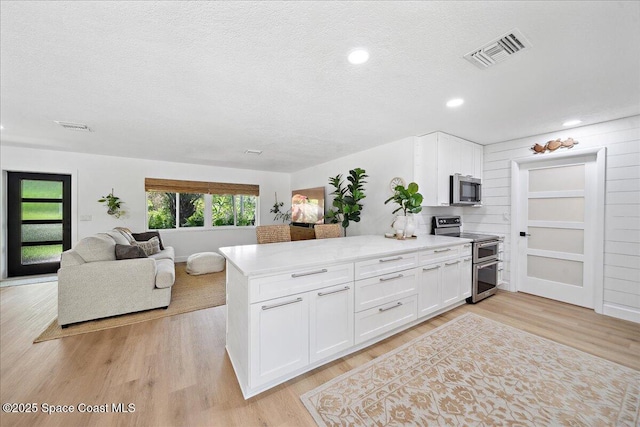 212 Ormond Dr, Indialantic, FL 32903 - kitchen featuring appliances with stainless steel finishes, light wood-style flooring, white cabinetry, a textured ceiling, and light countertops