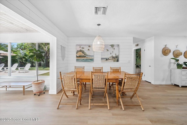 212 Ormond Dr, Indialantic, FL 32903 - dining space with light wood-style flooring, a textured ceiling, and wooden walls