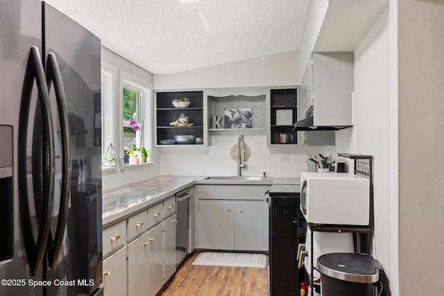 1949 36th Ave, Vero Beach, FL 32960 - kitchen with freestanding refrigerator, white microwave, a textured ceiling, stainless steel dishwasher, and light countertops