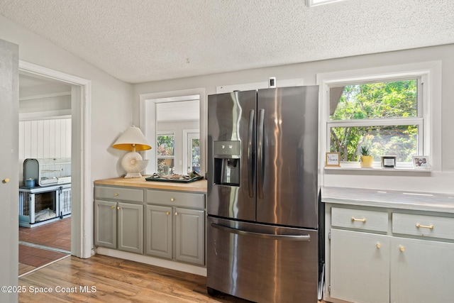 1949 36th Ave, Vero Beach, FL 32960 - kitchen featuring stainless steel fridge with ice dispenser, light countertops, light wood-style floors, gray cabinetry, and a textured ceiling