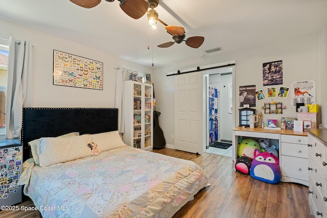 1949 36th Ave, Vero Beach, FL 32960 - bedroom with a barn door, wood finished floors, and a ceiling fan