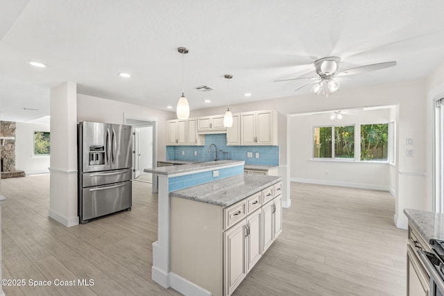4060 Rhonda Ct, Merritt Island, FL 32952 - kitchen featuring stainless steel refrigerator with ice dispenser, ceiling fan, a center island, tasteful backsplash, and light wood-style floors