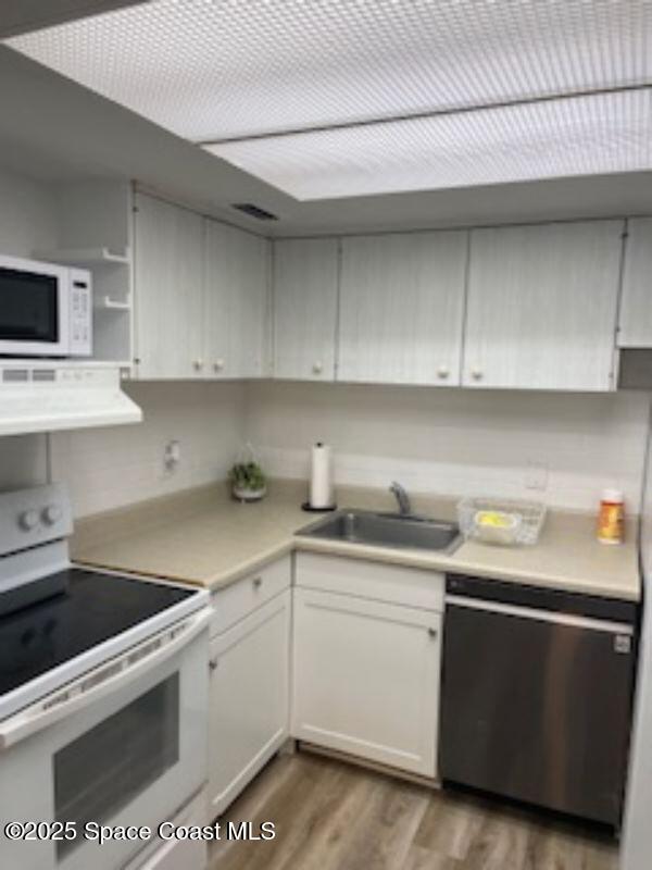 230 Columbia Dr Unit 208, Cape Canaveral, FL 32920 - kitchen featuring white appliances, ventilation hood, light countertops, wood finished floors, and white cabinetry