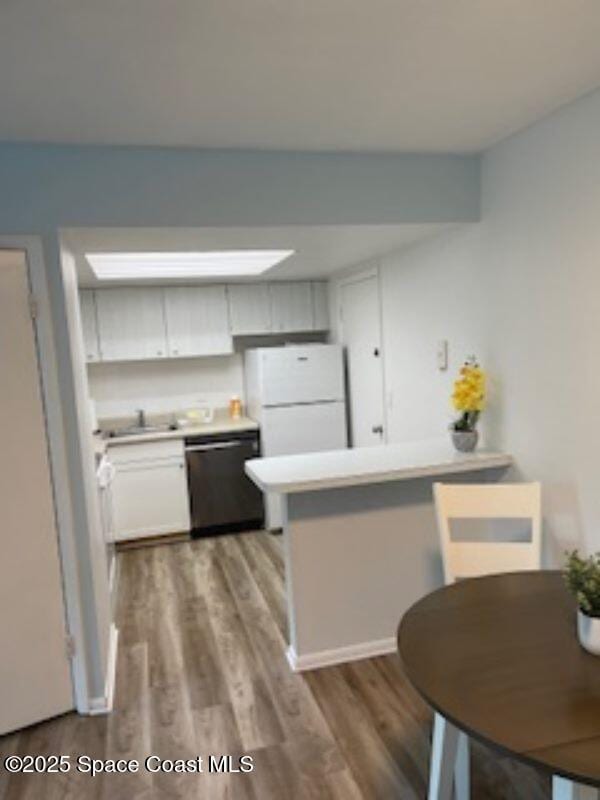 230 Columbia Dr Unit 208, Cape Canaveral, FL 32920 - kitchen with freestanding refrigerator, dishwasher, a peninsula, wood finished floors, and light countertops