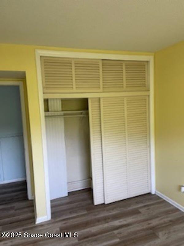 230 Columbia Dr Unit 208, Cape Canaveral, FL 32920 - unfurnished bedroom featuring a closet and dark wood-style flooring