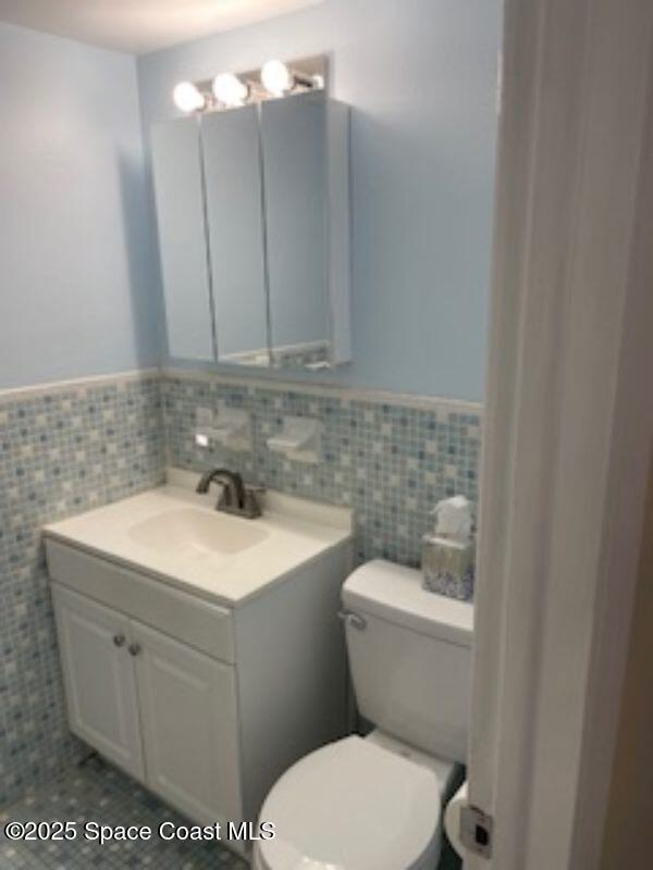 230 Columbia Dr Unit 208, Cape Canaveral, FL 32920 - half bath featuring vanity, wainscoting, and tile walls
