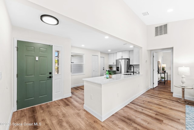 865 Southern Pine Trl, Rockledge, FL 32955 - kitchen with stainless steel fridge with ice dispenser, white cabinets, light wood finished floors, a peninsula, and light countertops