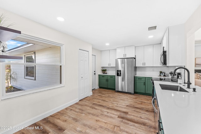 865 Southern Pine Trl, Rockledge, FL 32955 - kitchen featuring appliances with stainless steel finishes, green cabinets, light wood-style flooring, light countertops, and white cabinets