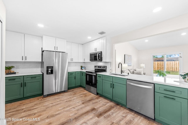 865 Southern Pine Trl, Rockledge, FL 32955 - kitchen with appliances with stainless steel finishes, green cabinets, white cabinetry, light wood-type flooring, and decorative backsplash