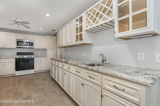 1250 Admiralty Blvd, Rockledge, FL 32955 - kitchen with white gas stove, stainless steel microwave, light wood-type flooring, recessed lighting, and light stone countertops