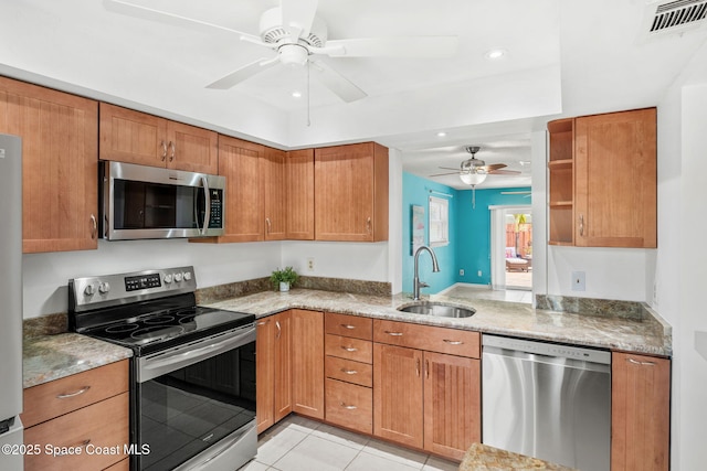 712 Sea Palm Ln, Satellite Beach, FL 32937 - kitchen with appliances with stainless steel finishes, ceiling fan, light tile patterned floors, brown cabinetry, and recessed lighting