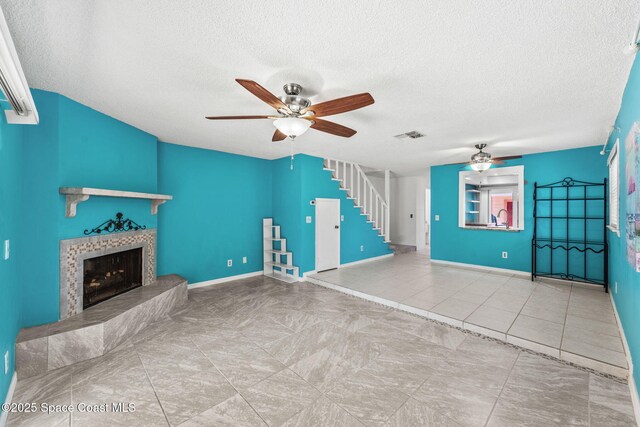 712 Sea Palm Ln, Satellite Beach, FL 32937 - unfurnished living room with a ceiling fan, stairs, a textured ceiling, and a tiled fireplace