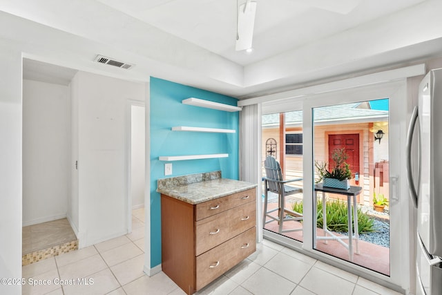 712 Sea Palm Ln, Satellite Beach, FL 32937 - kitchen with refrigerator, open shelves, brown cabinets, and light tile patterned floors