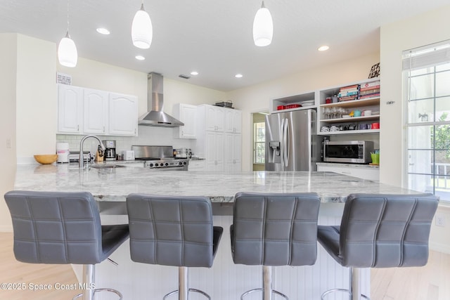 2123 Royal Oaks Dr, Rockledge, FL 32955 - kitchen with wall chimney range hood, stainless steel appliances, white cabinets, plenty of natural light, and recessed lighting