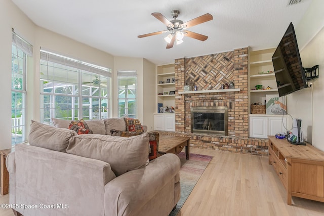 2123 Royal Oaks Dr, Rockledge, FL 32955 - living area featuring light wood finished floors, a ceiling fan, built in shelves, and a fireplace