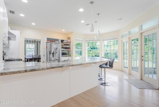 2123 Royal Oaks Dr, Rockledge, FL 32955 - kitchen featuring stainless steel fridge, light stone countertops, a peninsula, light wood-type flooring, and recessed lighting