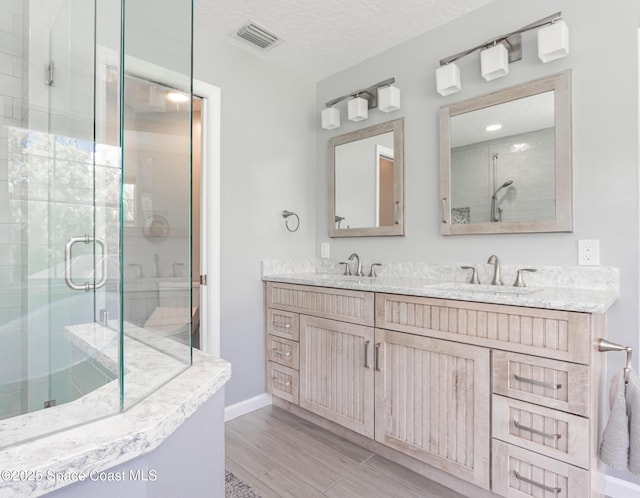 2123 Royal Oaks Dr, Rockledge, FL 32955 - bathroom featuring double vanity, a stall shower, wood finished floors, and a textured ceiling