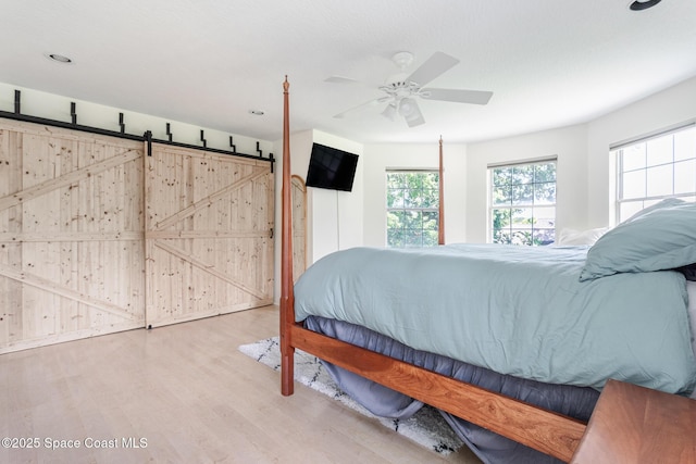 2123 Royal Oaks Dr, Rockledge, FL 32955 - bedroom with wood finished floors, a barn door, a ceiling fan, and recessed lighting
