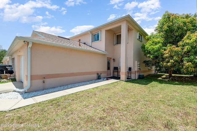 112 Plover Ln Unit 6-33, Rockledge, FL 32955 - rear view of house with stucco siding, a yard, and roof with shingles