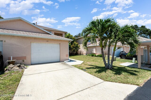 112 Plover Ln Unit 6-33, Rockledge, FL 32955 - view of side of property with stucco siding, driveway, a yard, and a garage