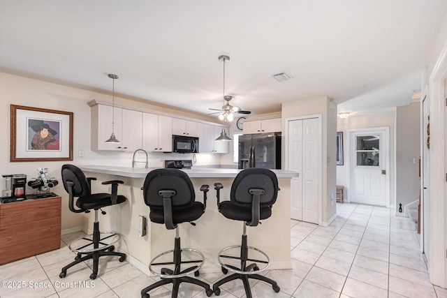 112 Plover Ln Unit 6-33, Rockledge, FL 32955 - kitchen featuring black appliances, a peninsula, light countertops, a kitchen breakfast bar, and ceiling fan