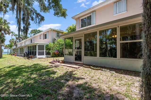 112 Plover Ln Unit 6-33, Rockledge, FL 32955 - back of house featuring a sunroom, stucco siding, and a lawn