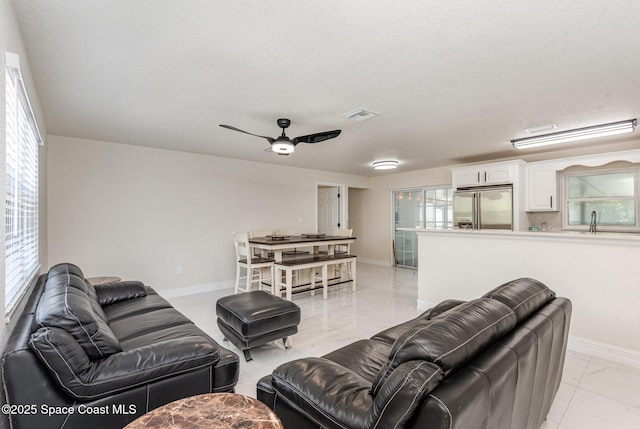 1245 Arlington Cir, Merritt Island, FL 32952 - living area with light marble finish flooring, ceiling fan, healthy amount of natural light, and a textured ceiling
