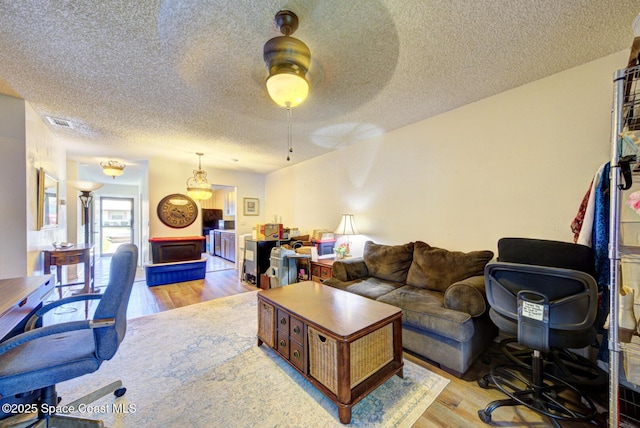 1240 Cheney Hwy Unit F, Titusville, FL 32780 - living area featuring light wood finished floors, a textured ceiling, and ceiling fan