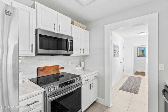 3127 Marshall Dr, Melbourne, FL 32901 - kitchen with appliances with stainless steel finishes, white cabinetry, light tile patterned floors, decorative backsplash, and a textured ceiling