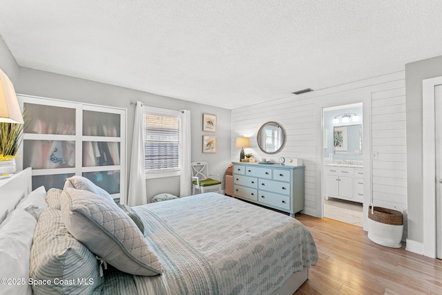 3127 Marshall Dr, Melbourne, FL 32901 - bedroom featuring light wood-style flooring, a textured ceiling, and ensuite bath