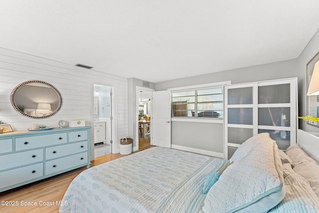 3127 Marshall Dr, Melbourne, FL 32901 - bedroom with light wood-style floors, wooden walls, and ensuite bathroom