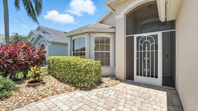 7927 Citrus Creek Dr, Melbourne, FL 32940 - doorway to property with stucco siding and a shingled roof
