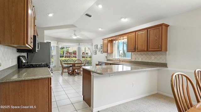 7927 Citrus Creek Dr, Melbourne, FL 32940 - kitchen featuring brown cabinetry, tasteful backsplash, a ceiling fan, a peninsula, and recessed lighting
