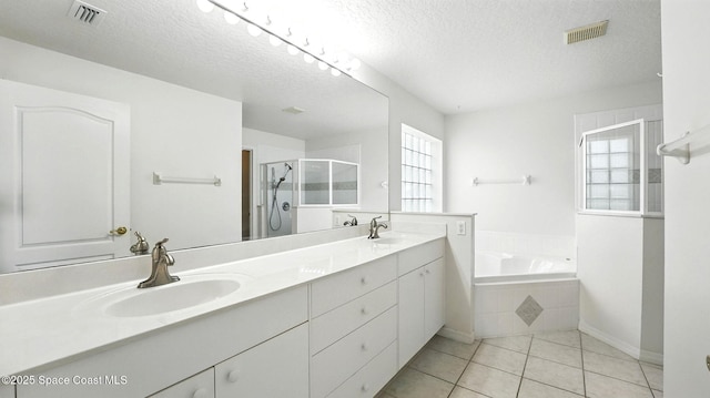 7927 Citrus Creek Dr, Melbourne, FL 32940 - bathroom featuring a shower stall, a garden tub, double vanity, tile patterned floors, and a textured ceiling