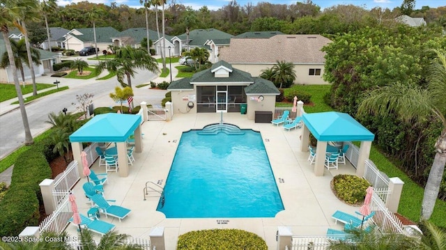 7927 Citrus Creek Dr, Melbourne, FL 32940 - community pool with a sunroom, a fenced backyard, a patio, a residential view, and a gate