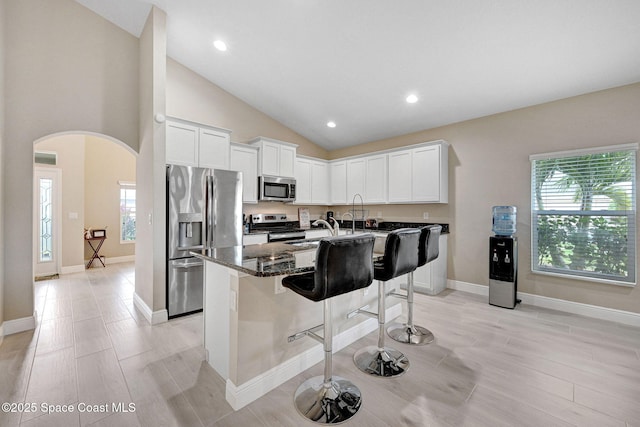2248 Attilburgh Blvd, West Melbourne, FL 32904 - kitchen with stainless steel appliances, arched walkways, a breakfast bar area, a center island with sink, and white cabinetry