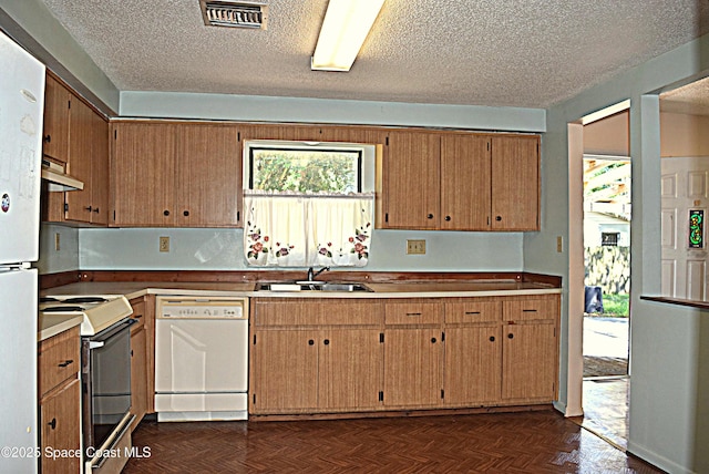 2508 Palmetto Dr, Cocoa, FL 32926 - kitchen with white appliances, under cabinet range hood, a textured ceiling, and brown cabinetry
