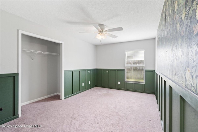 781 Dinner St NE, Palm Bay, FL 32907 - unfurnished bedroom featuring carpet flooring, wainscoting, a closet, a ceiling fan, and a textured ceiling