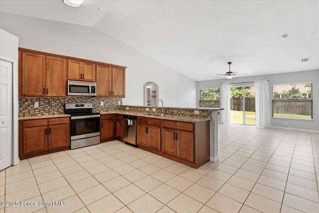 781 Dinner St NE, Palm Bay, FL 32907 - kitchen with stainless steel appliances, vaulted ceiling, a ceiling fan, decorative backsplash, and brown cabinets