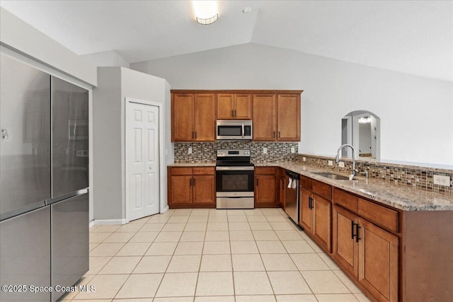 781 Dinner St NE, Palm Bay, FL 32907 - kitchen with stainless steel appliances, arched walkways, brown cabinetry, tasteful backsplash, and vaulted ceiling