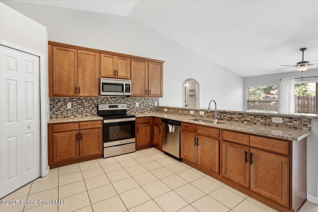 781 Dinner St NE, Palm Bay, FL 32907 - kitchen with appliances with stainless steel finishes, brown cabinetry, a peninsula, tasteful backsplash, and vaulted ceiling