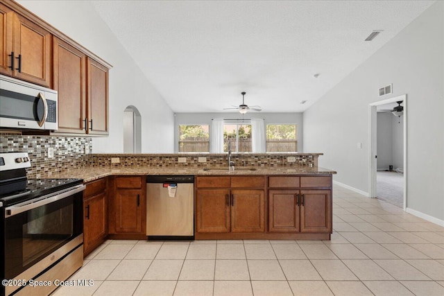 781 Dinner St NE, Palm Bay, FL 32907 - kitchen featuring appliances with stainless steel finishes, a ceiling fan, backsplash, vaulted ceiling, and brown cabinetry