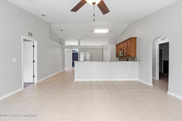 781 Dinner St NE, Palm Bay, FL 32907 - kitchen featuring appliances with stainless steel finishes, open floor plan, brown cabinetry, a ceiling fan, and a peninsula