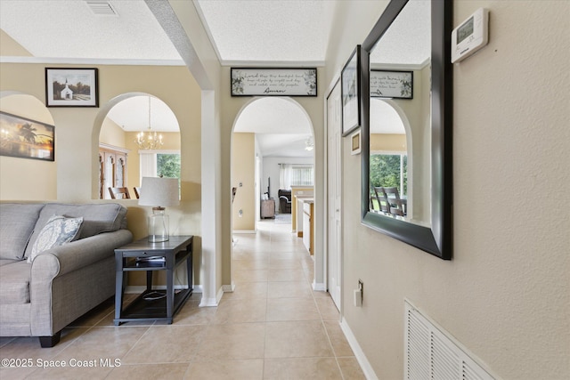 149 Hawthorne Ln NE, Palm Bay, FL 32907 - hallway featuring arched walkways, light tile patterned flooring, plenty of natural light, and a chandelier