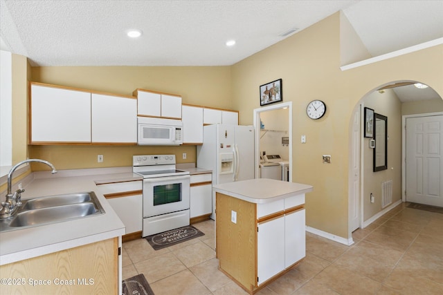 149 Hawthorne Ln NE, Palm Bay, FL 32907 - kitchen with white appliances, arched walkways, vaulted ceiling, separate washer and dryer, and a center island