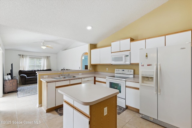 149 Hawthorne Ln NE, Palm Bay, FL 32907 - kitchen featuring white appliances, vaulted ceiling, a textured ceiling, a peninsula, and light tile patterned floors
