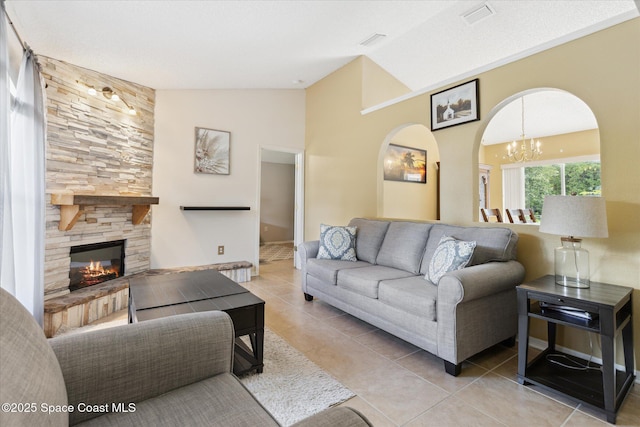 149 Hawthorne Ln NE, Palm Bay, FL 32907 - tiled living area featuring vaulted ceiling, arched walkways, a chandelier, and a stone fireplace