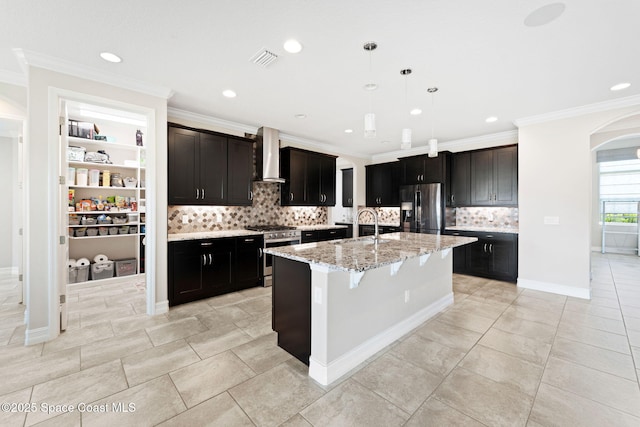 7684 Poulicny Ln, Melbourne, FL 32940 - kitchen featuring appliances with stainless steel finishes, wall chimney range hood, arched walkways, decorative backsplash, and light stone countertops