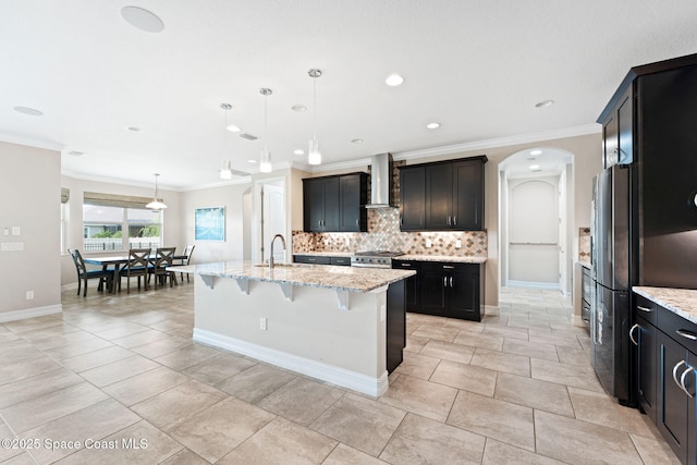 7684 Poulicny Ln, Melbourne, FL 32940 - kitchen featuring wall chimney exhaust hood, crown molding, backsplash, arched walkways, and a kitchen breakfast bar